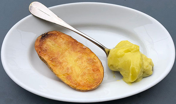 Pomme de terre servie dans une assiette avec une cuillère d'aïoli